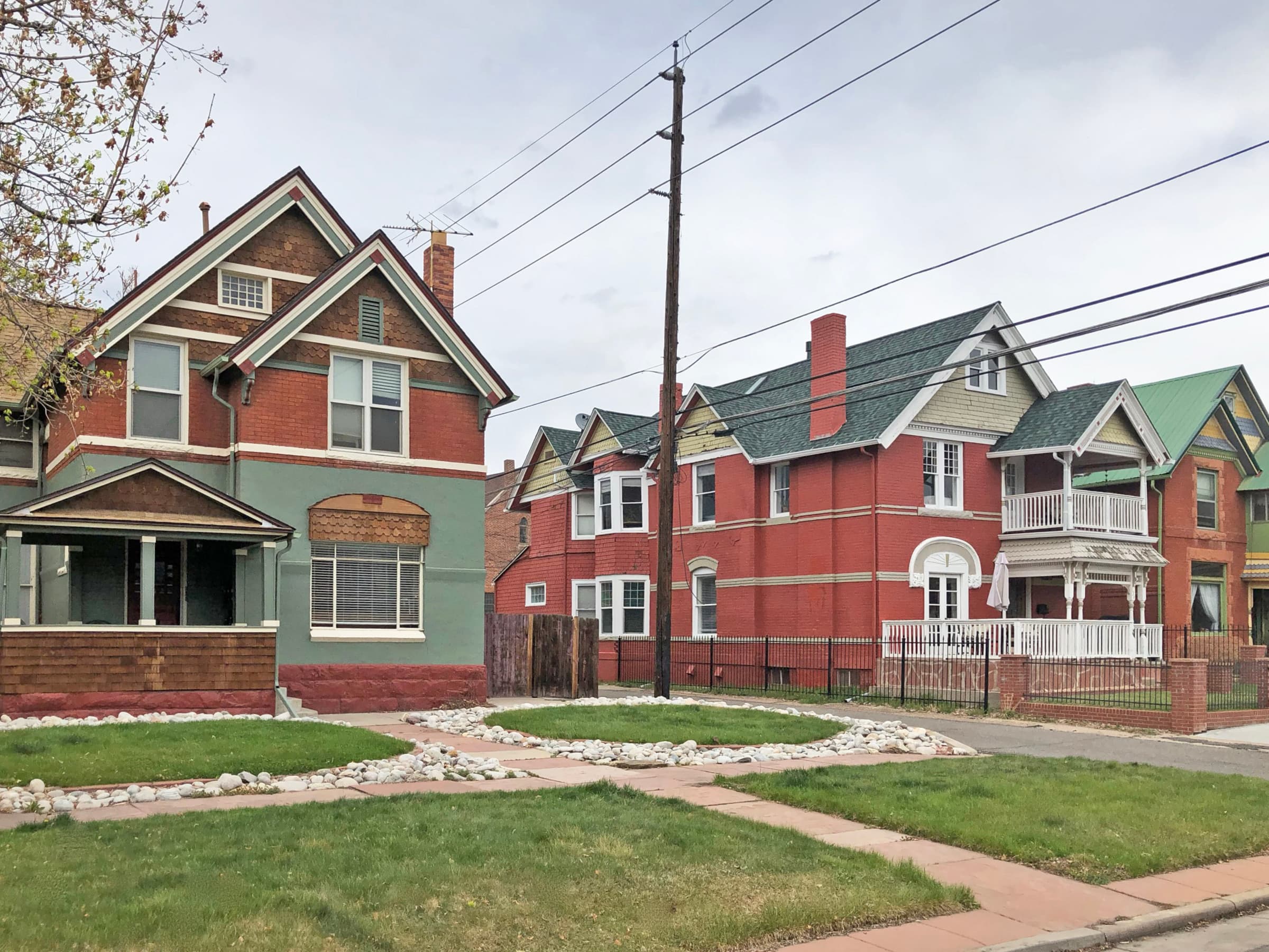 Late-Victorian brick homes with covered porches along a residential block in Baker, Denver
