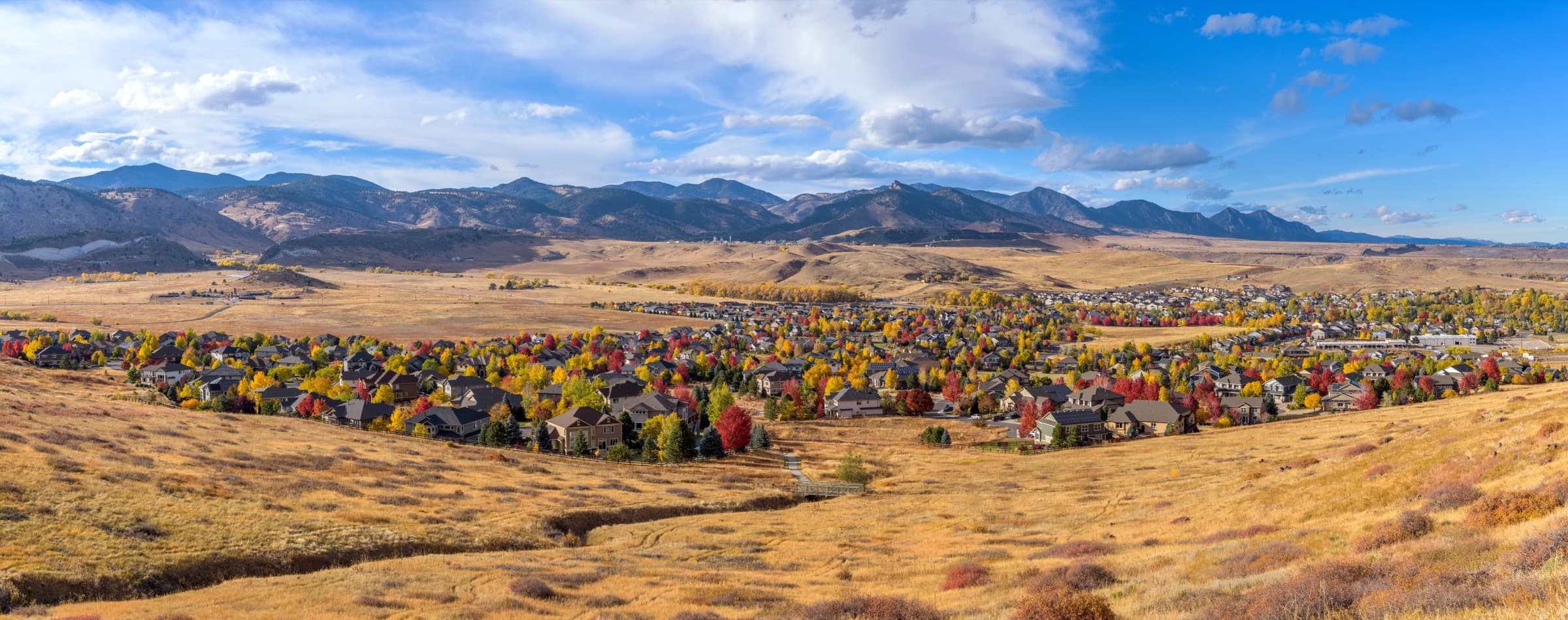 Panoramic view of a neighborhood in fall color below the Front Range foothills